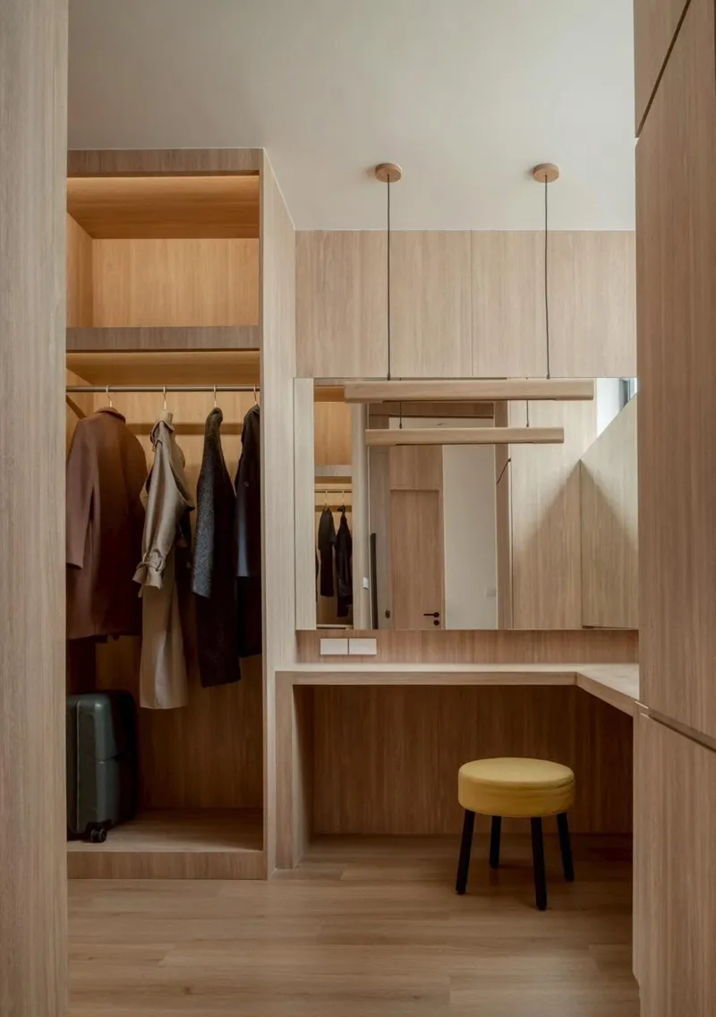 Dressing area with open wardrobe alcove, vanity desk, and suspended pendant lights