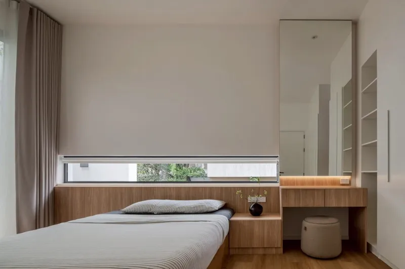 Bedroom with integrated timber bed platform and horizontal window slot framing greenery outside