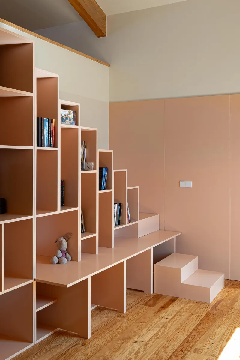 Integrated staircase and shelving unit in pink with stepped geometric compartments on timber flooring