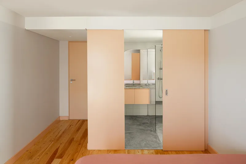 View through pink sliding panels into bathroom with glass shower enclosure and concrete floor