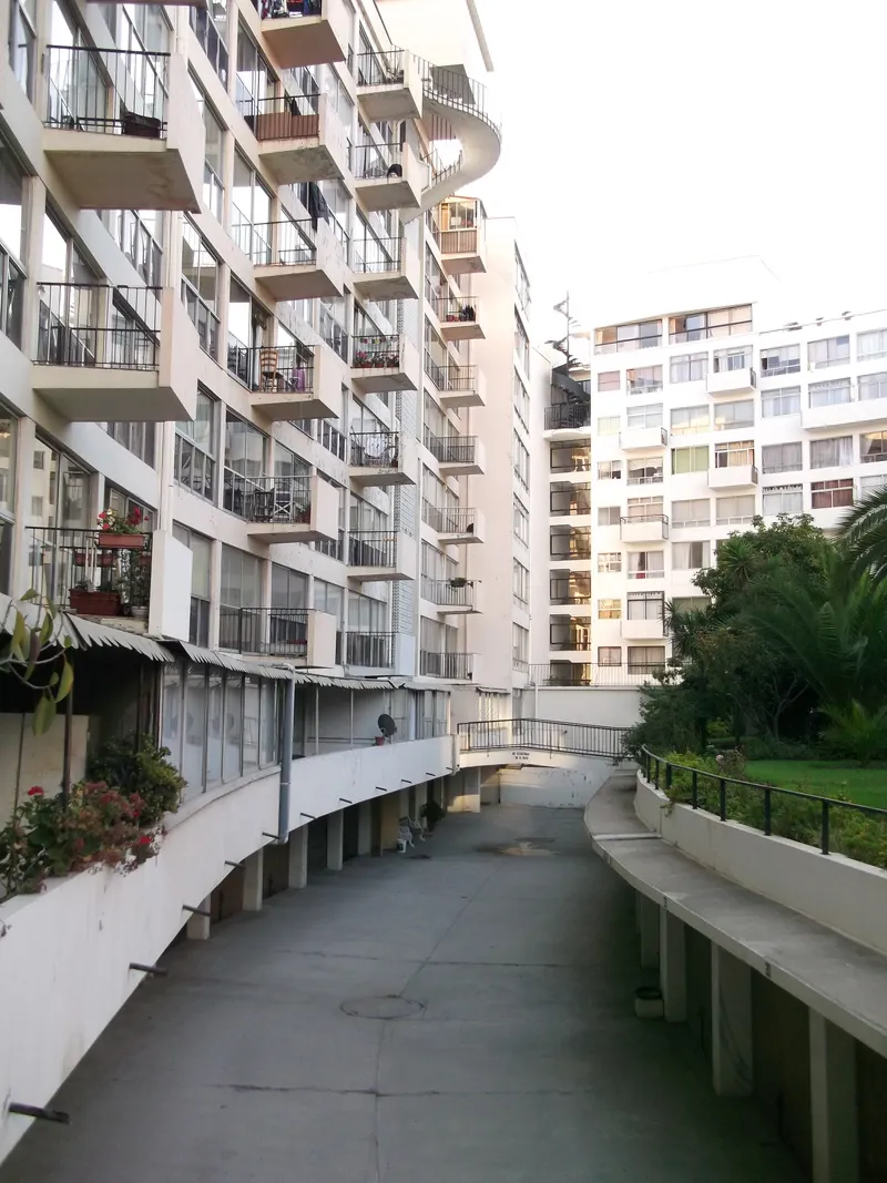 Curved pedestrian ramp between residential towers with a person walking in the distance at dusk