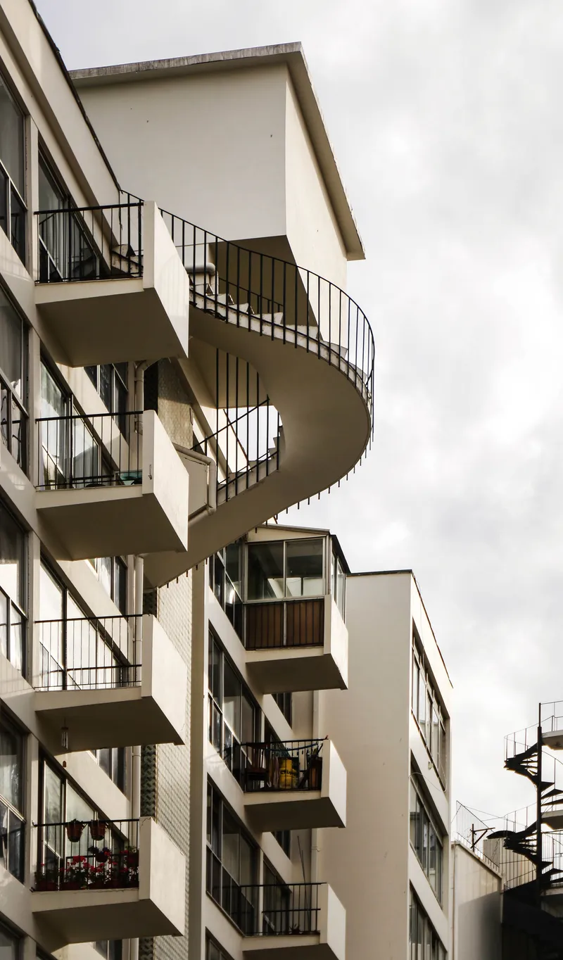 Projecting circular stair tower with metal railings against an overcast sky
