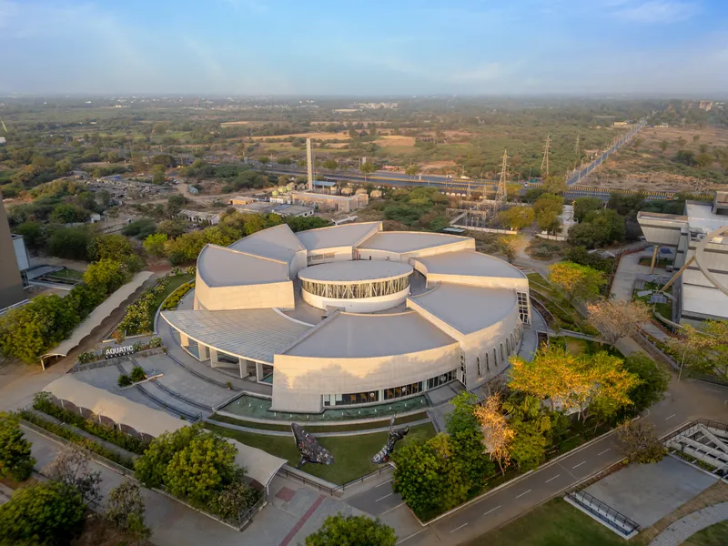 Drone view of the radial roof petals extending from a central glazed drum in afternoon light
