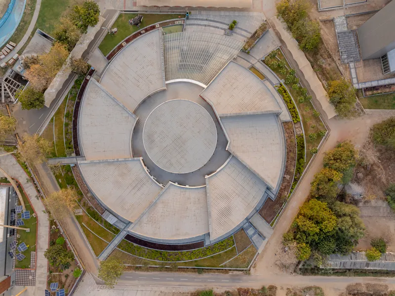 Top-down view of the circular paved plaza with radial symmetry and planted borders between roof sections
