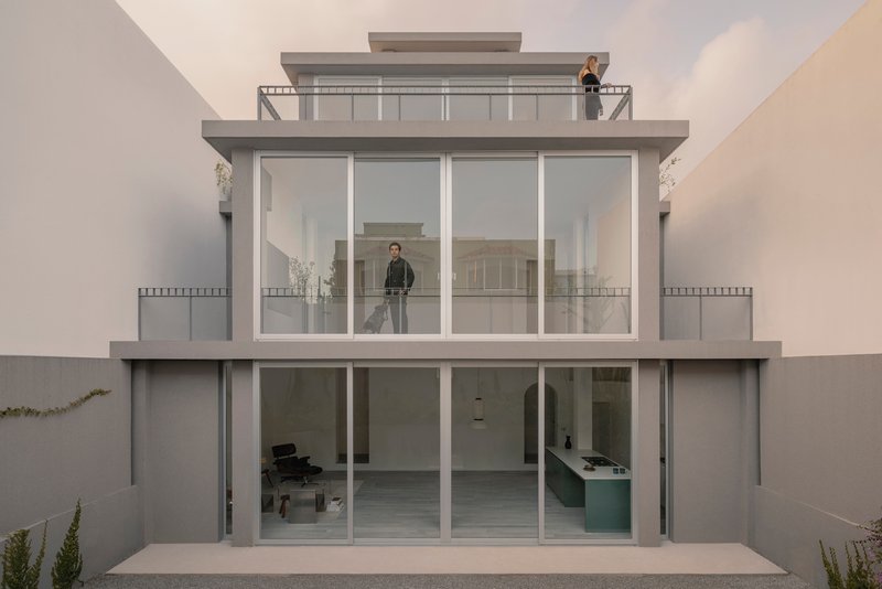 Rear facade with stacked glazed volumes and recessed balconies under overcast sky