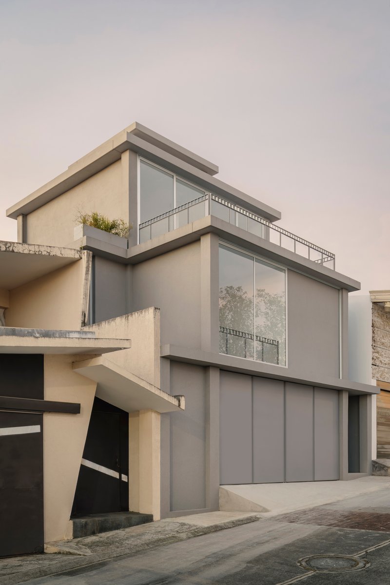 Street view of the stacked facade with grey paneling and vertical balconies under an overcast sky