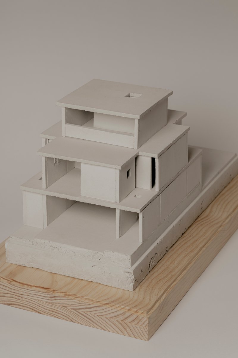 Corner view of the terraced model with layered horizontal planes on wood and concrete plinths