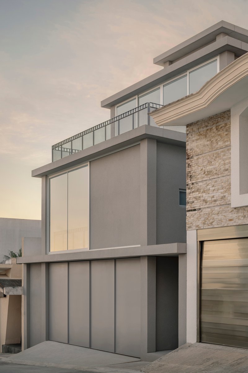 Corner elevation showing grey panel cladding and stone veneer with glass balustrades at dusk