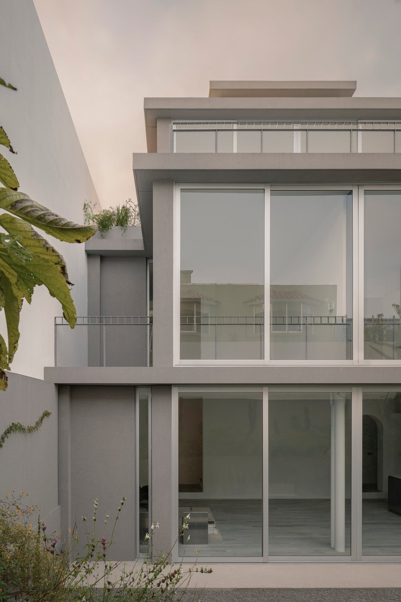 Rear elevation with sliding glass doors and planted roof terrace framed by palms and ferns