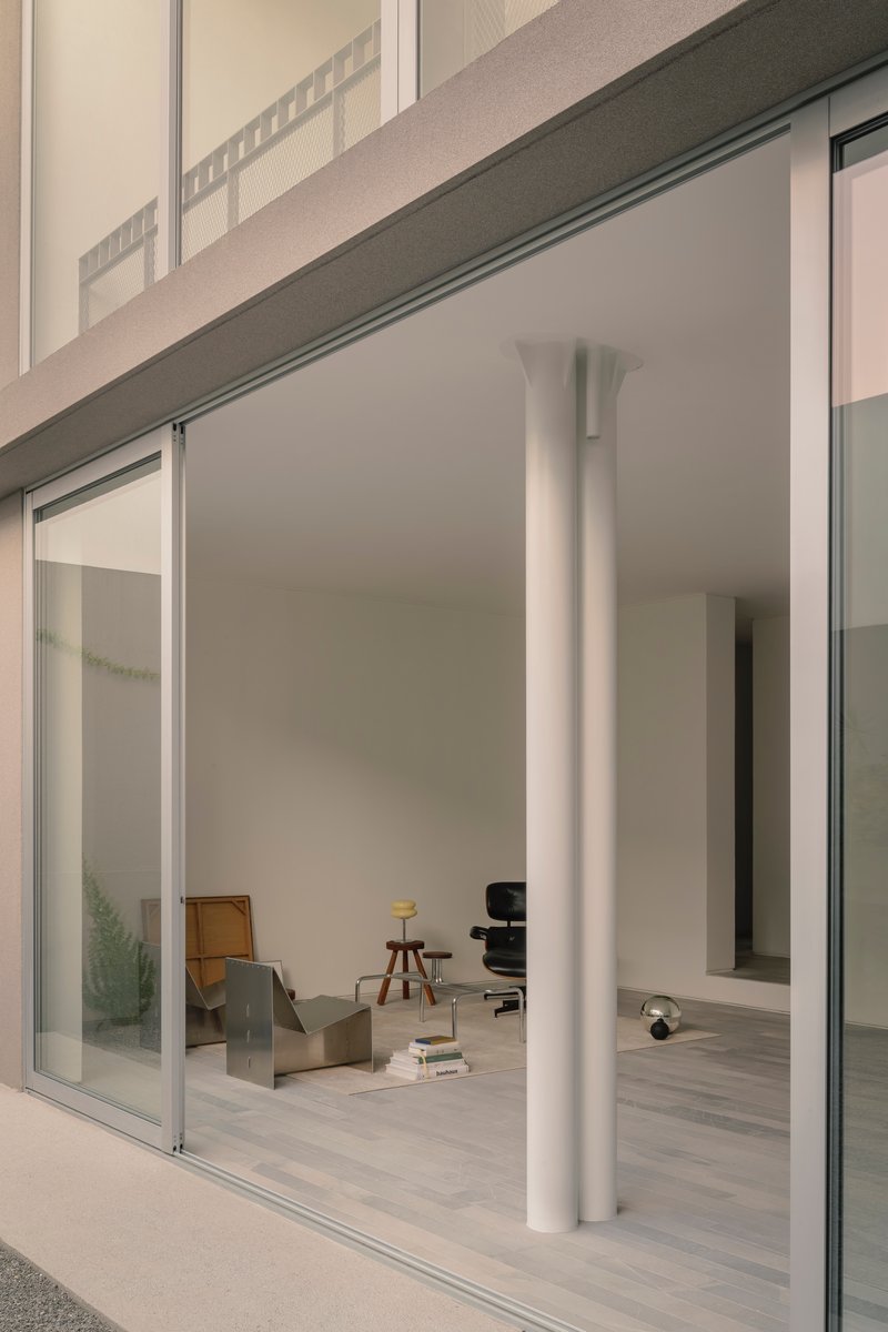 Interior view through open sliding doors showing white column and furniture in soft afternoon light