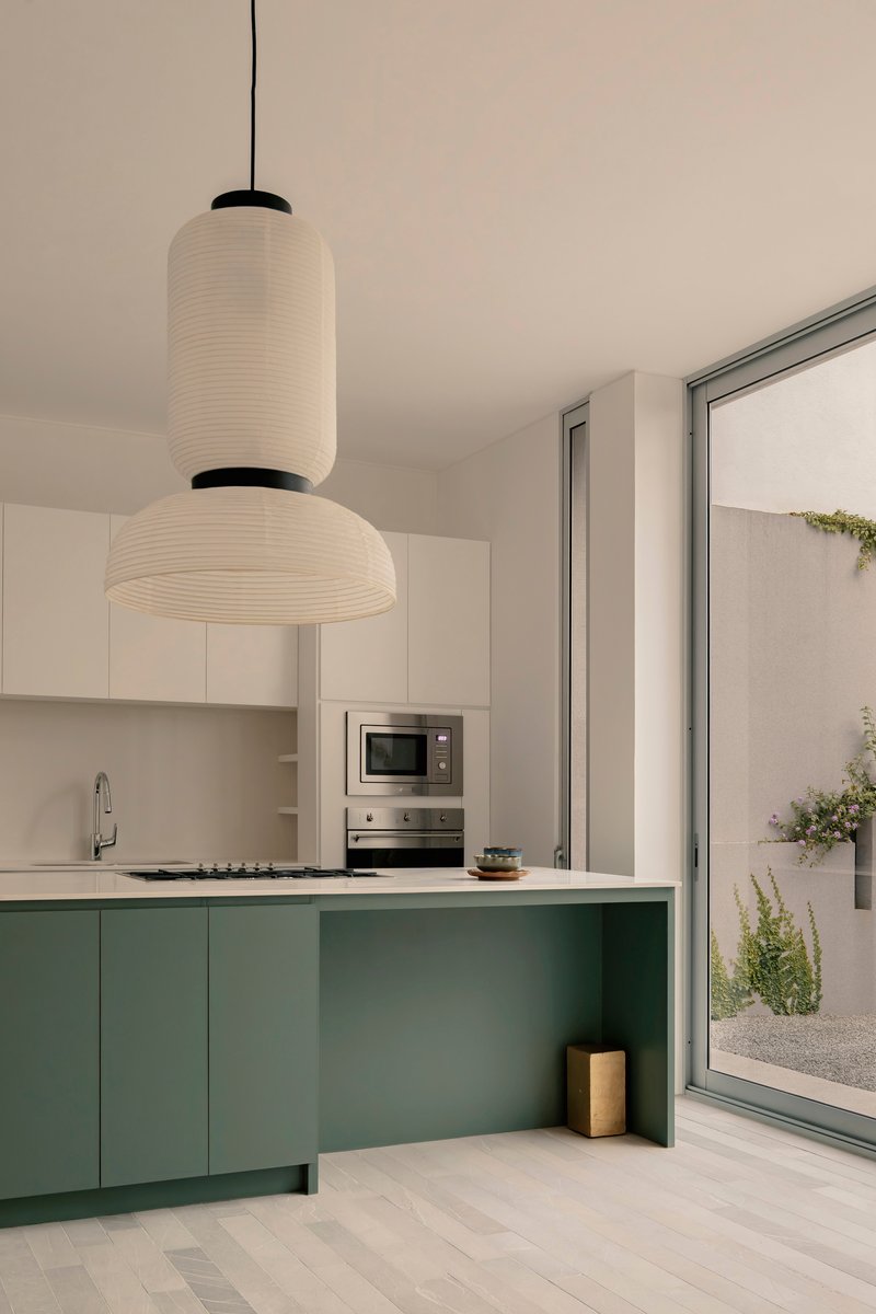 Kitchen with green lower cabinets and white uppers beneath two stacked paper lantern pendants