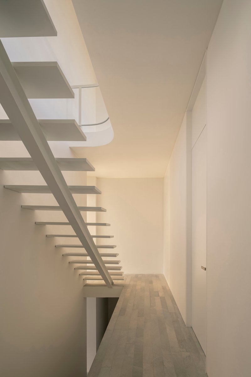 View along a hallway showing the floating staircase treads cantilevered from a central white stringer