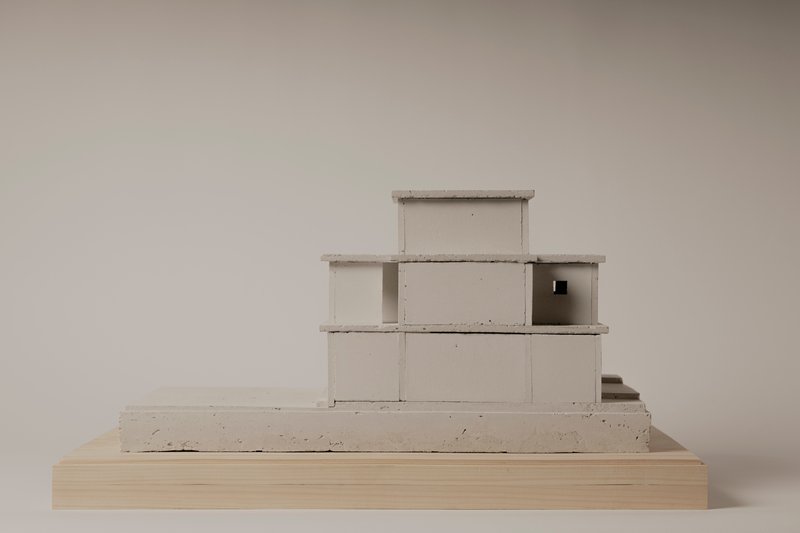 Concrete model showing a stepped volumetric composition on a wooden base