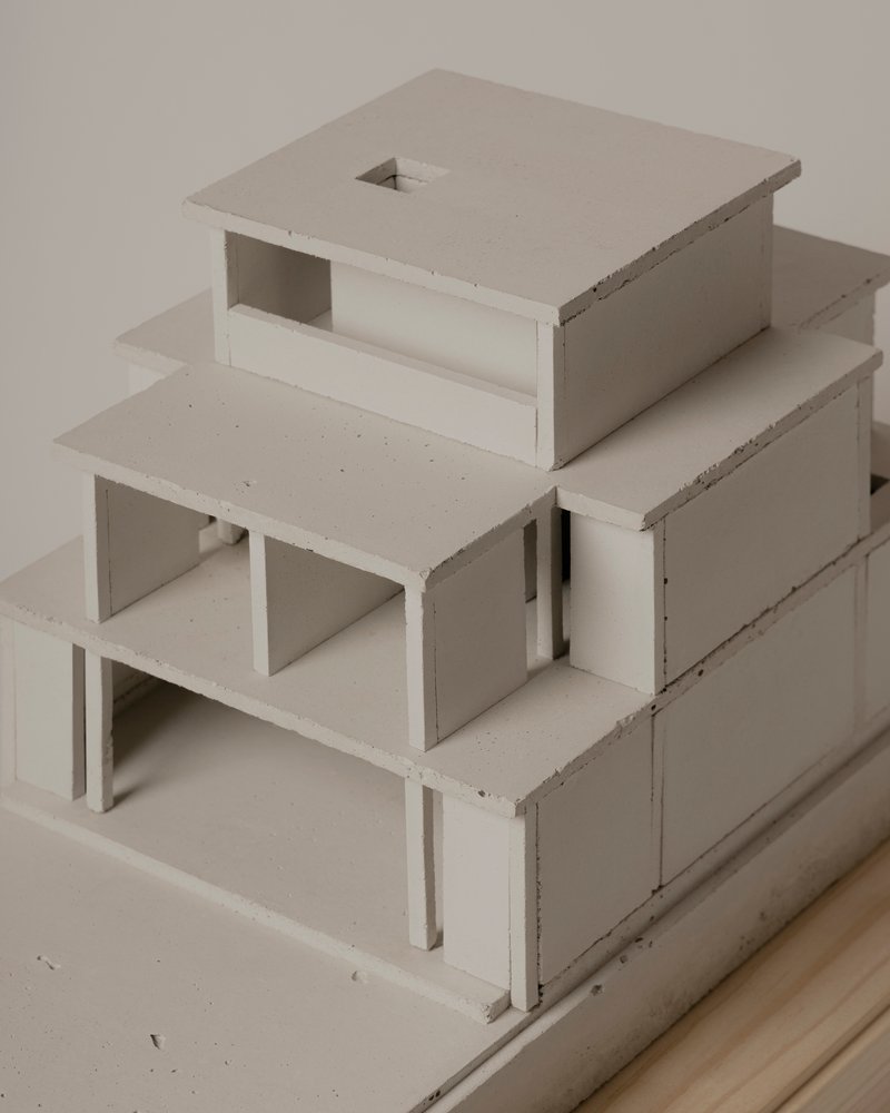 Physical model showing tiered volumes with open terraces and a central skylight on a timber base