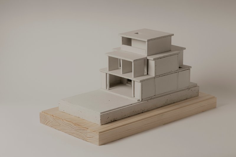 Side view of the stepped massing model with exposed interior spaces and concrete plinth