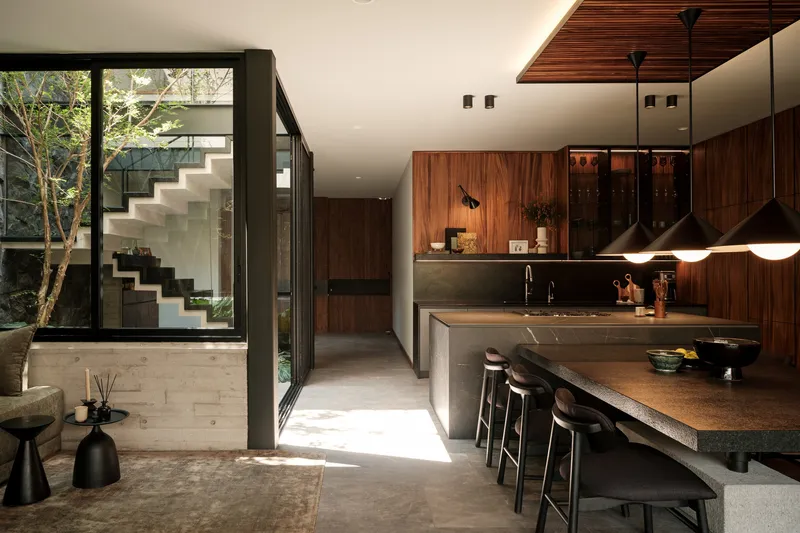 Kitchen island with dark stone countertop overlooking an interior courtyard through floor-to-ceiling glazing