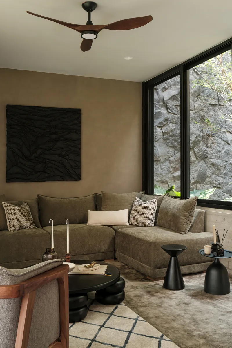 Seating area with corner glazing framing a view of rough-hewn stone courtyard wall and planting