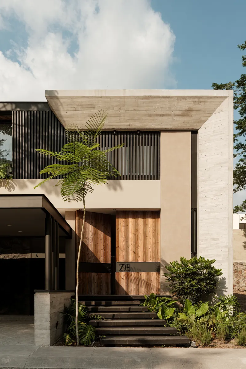 Entry facade showing board-formed concrete frame, vertical wood screens, and timber entry steps