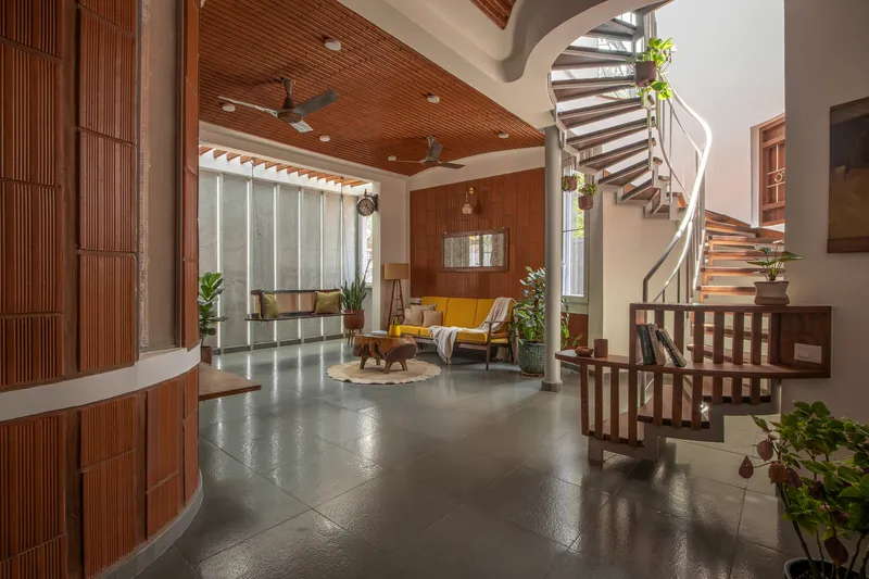 Double-height living space with curved timber ceiling, spiral staircase and potted plants