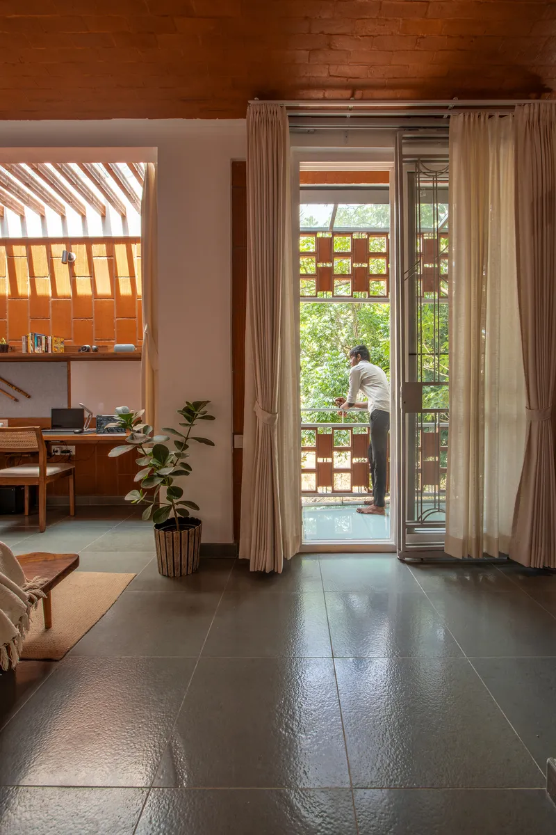 View through living room to balcony with perforated brick screen where a person stands