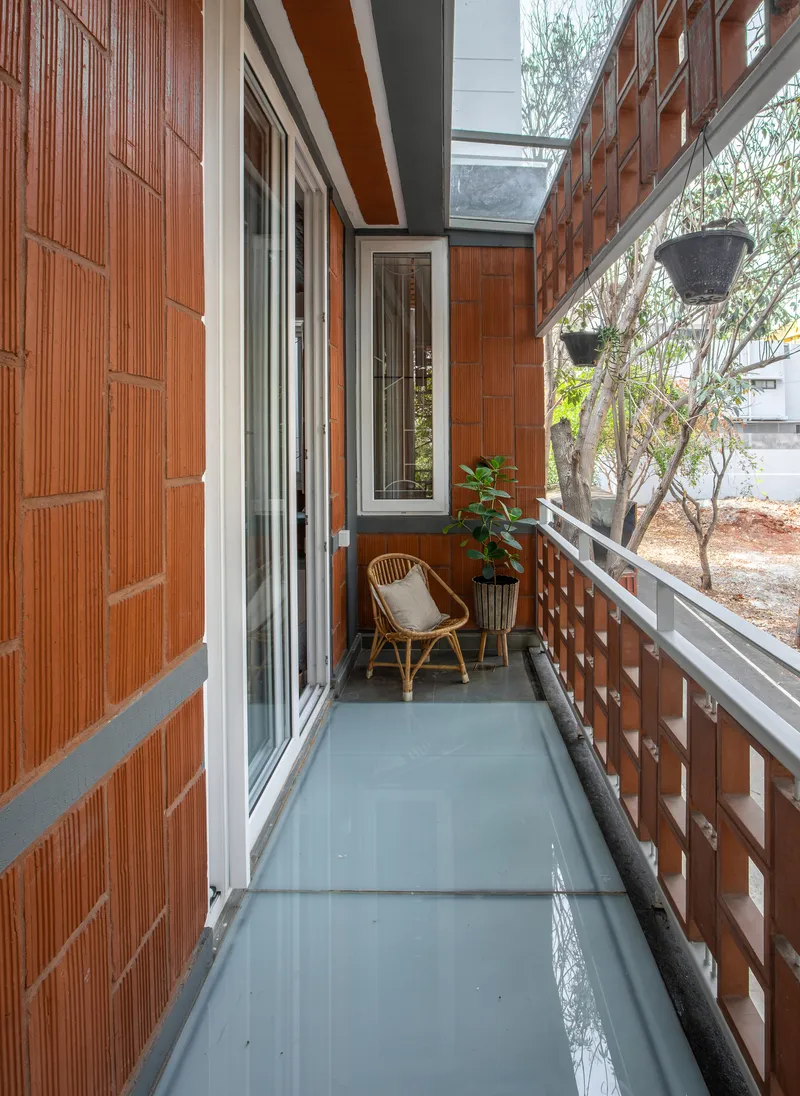 Narrow balcony with grey painted floor enclosed by terracotta tile walls and railing