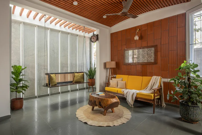 Seating area under striped timber ceiling with tall concrete panels and sheer curtains filtering daylight