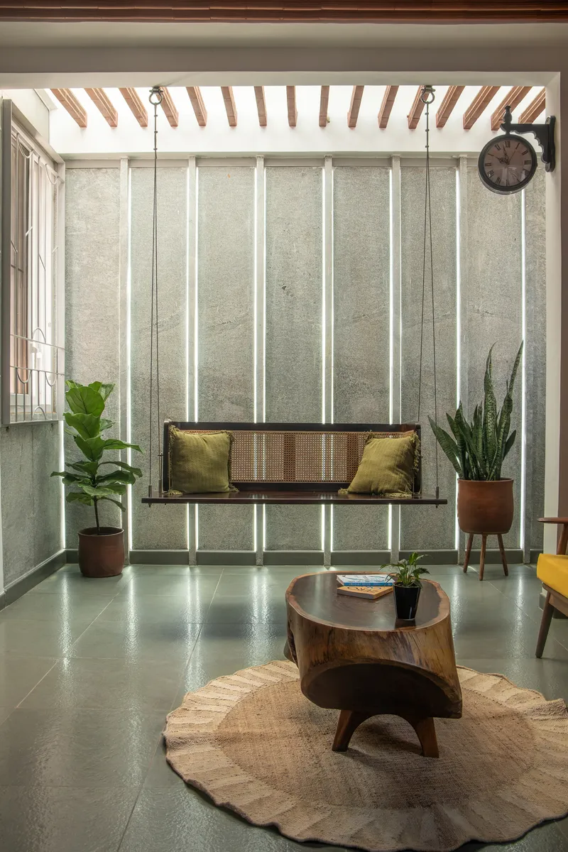 Living room with vertical backlit panels in the concrete wall and a suspended cane swing seat