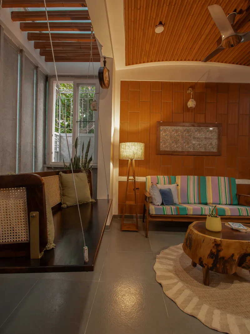Living area with curved timber ceiling vault and suspended swing near the window at dusk