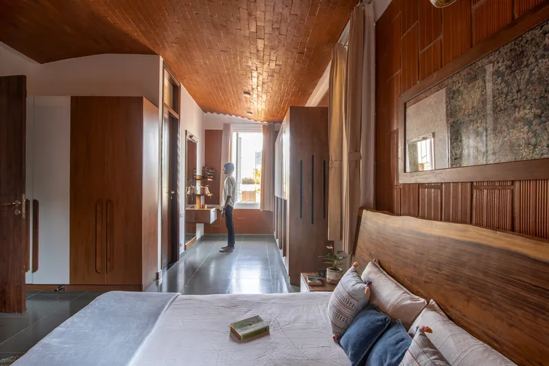 Bedroom with vaulted brick ceiling and timber paneling as a person stands in the doorway