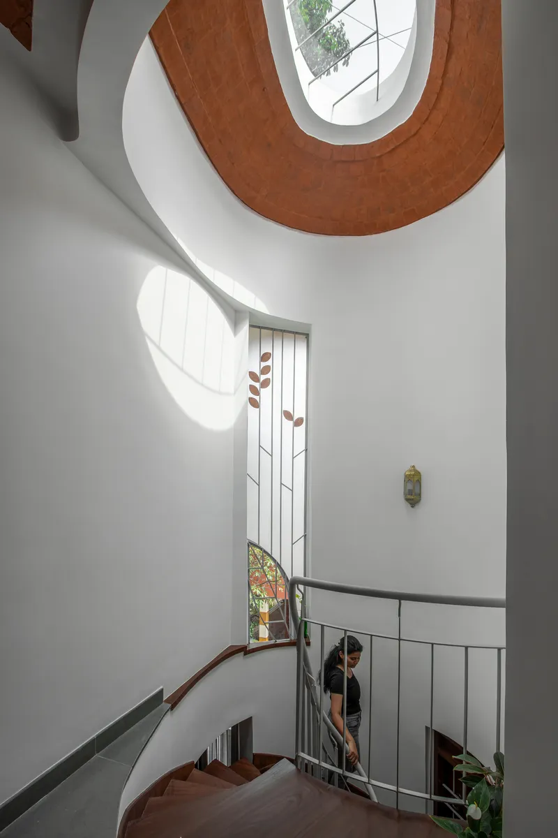 Upward view of the spiral staircase with white walls and timber treads in natural light