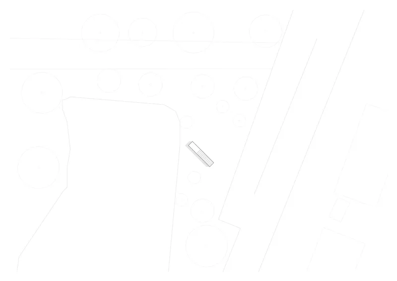 Site plan drawing depicting the elongated building form on sloping terrain between organic boundaries