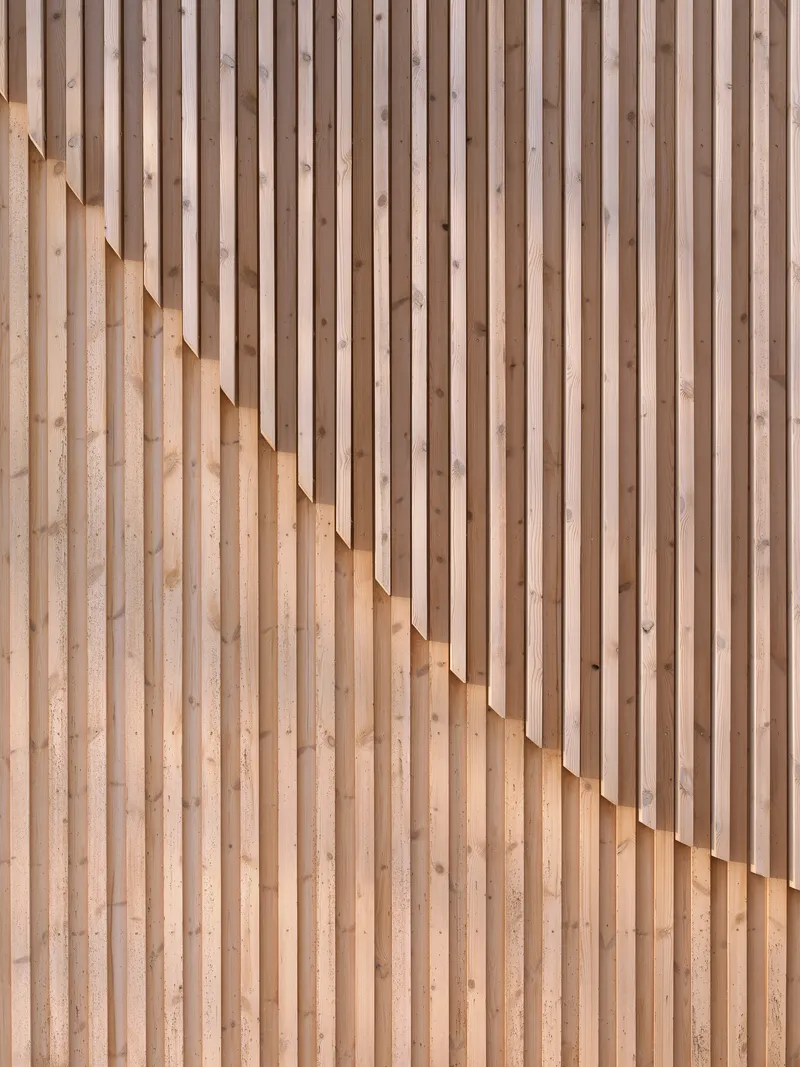 Close-up of staggered timber slat wall creating a rhythmic pattern of light and shadow