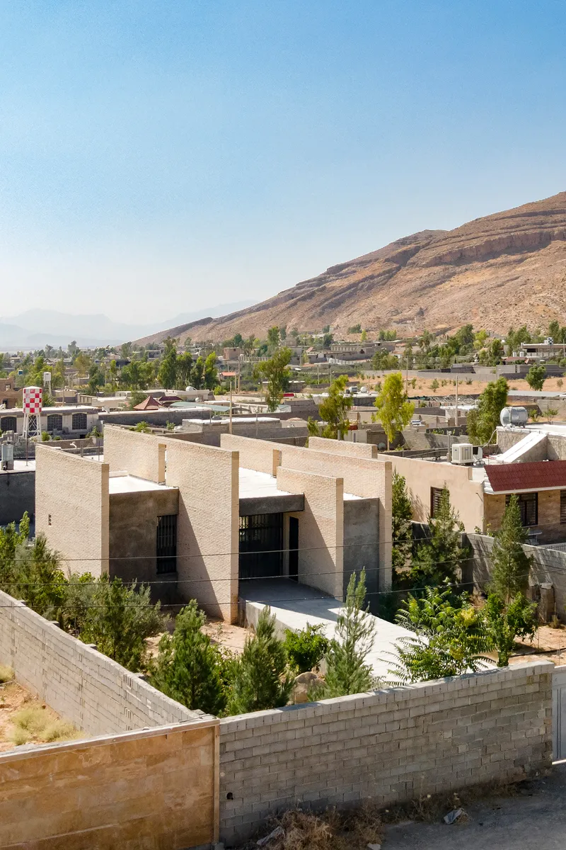 Rooftop view of the residence set against a hillside neighborhood with young trees in foreground