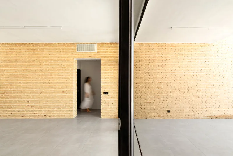 Interior room with pale brick walls and a doorway framing a figure passing through in motion
