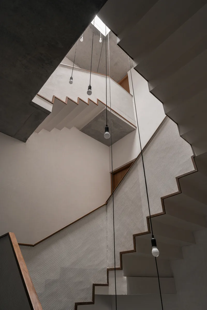 Upward view of multi-level stairwell with pendant lights hanging through the skylit void