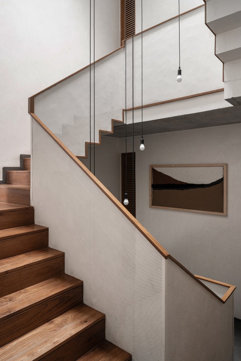 Timber staircase with mesh-paneled balustrade and pendant lights descending through the stairwell