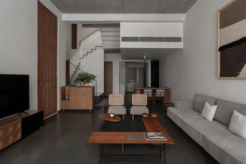 Double-height living room with concrete ceiling, central staircase and polished dark floor