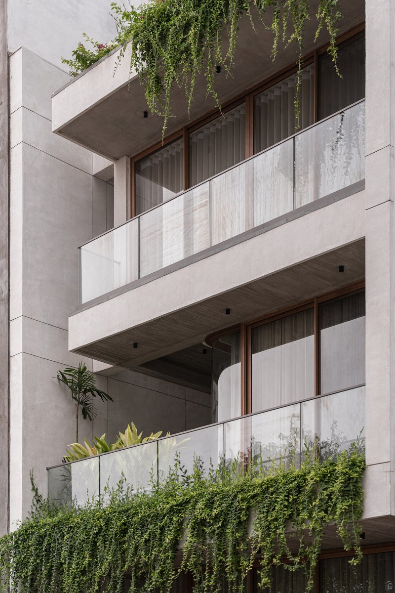 Concrete balconies with glass railings, timber screens and trailing plants above each terrace