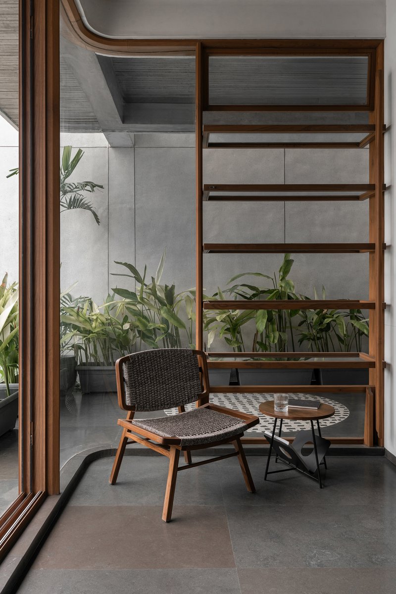 Timber shelving unit beside glazed corner with potted palms in an interior courtyard