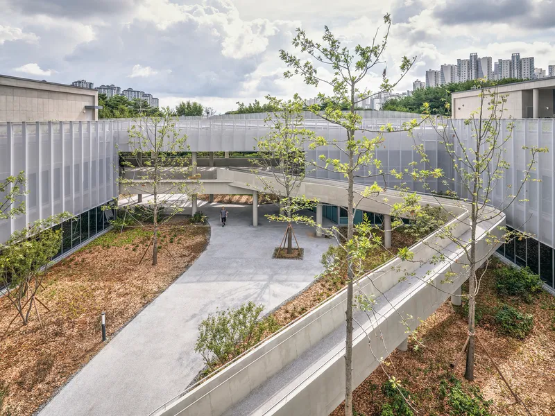 Aerial view of the curved pathway weaving through landscaped berms with young trees under a cloudy sky