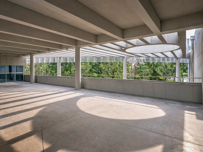 Interior colonnade with concrete coffers casting circular shadows across the floor in afternoon light