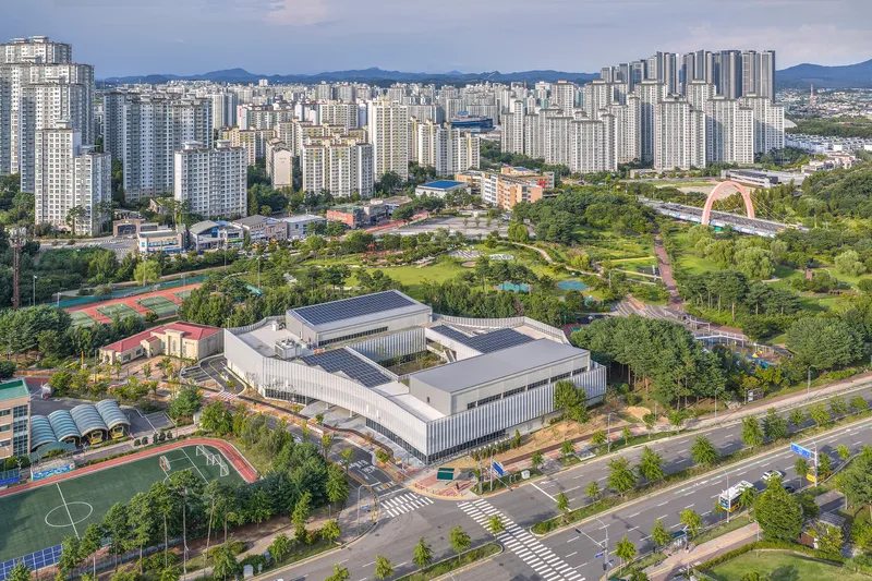 Aerial view of the interlocking white volumes surrounded by parkland and high-rise residential development