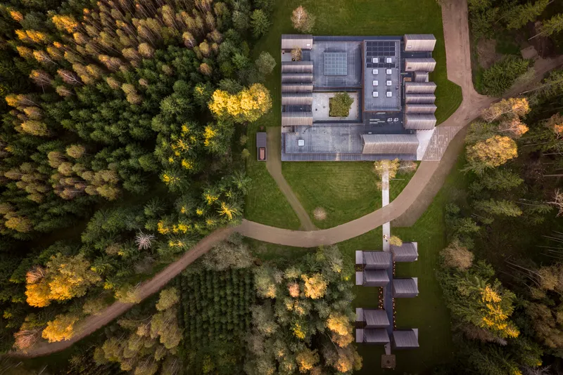 Aerial view showing the H-shaped plan with central courtyard surrounded by autumn forest