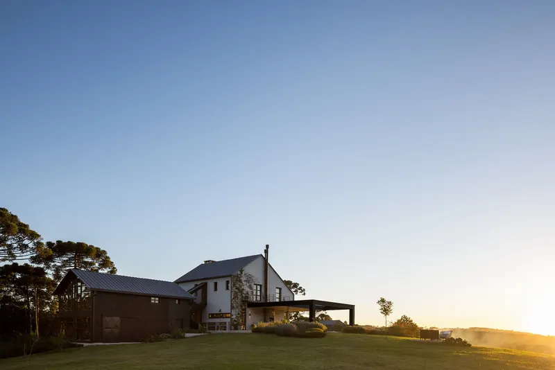 House with covered terrace and metal roofs on a lawn at sunset with golden light