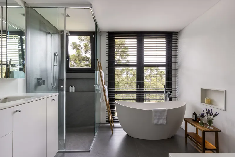 Bathroom with freestanding tub, glass-enclosed shower and horizontal timber blinds framing the window