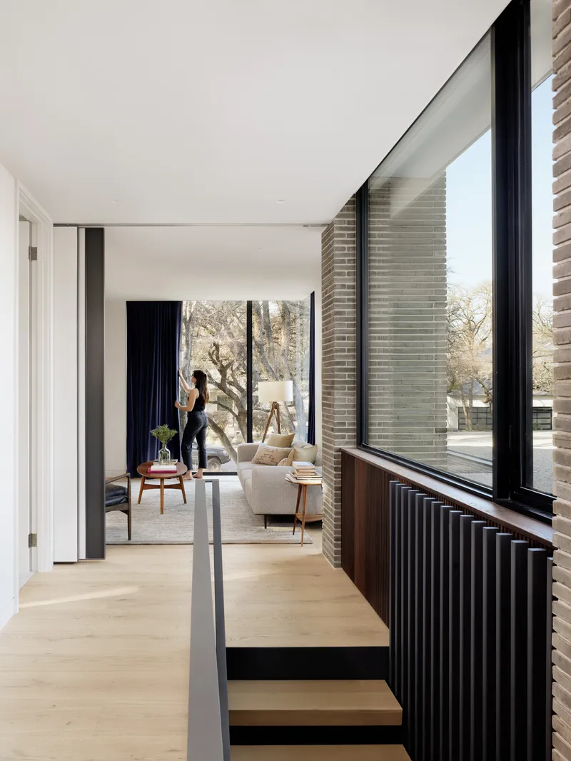 Interior hallway with fluted wood radiator cover below corner windows framing the landscape