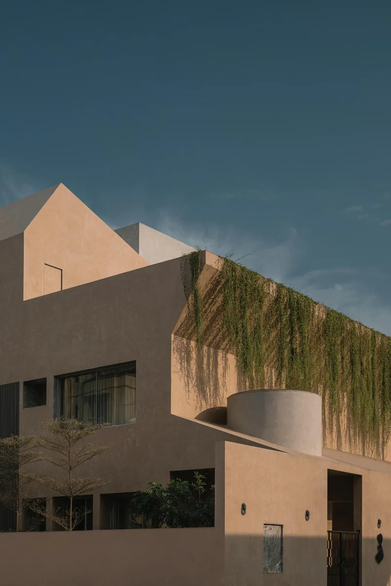 Facade detail featuring planted upper terrace with trailing vegetation above a cylindrical cantilevered element