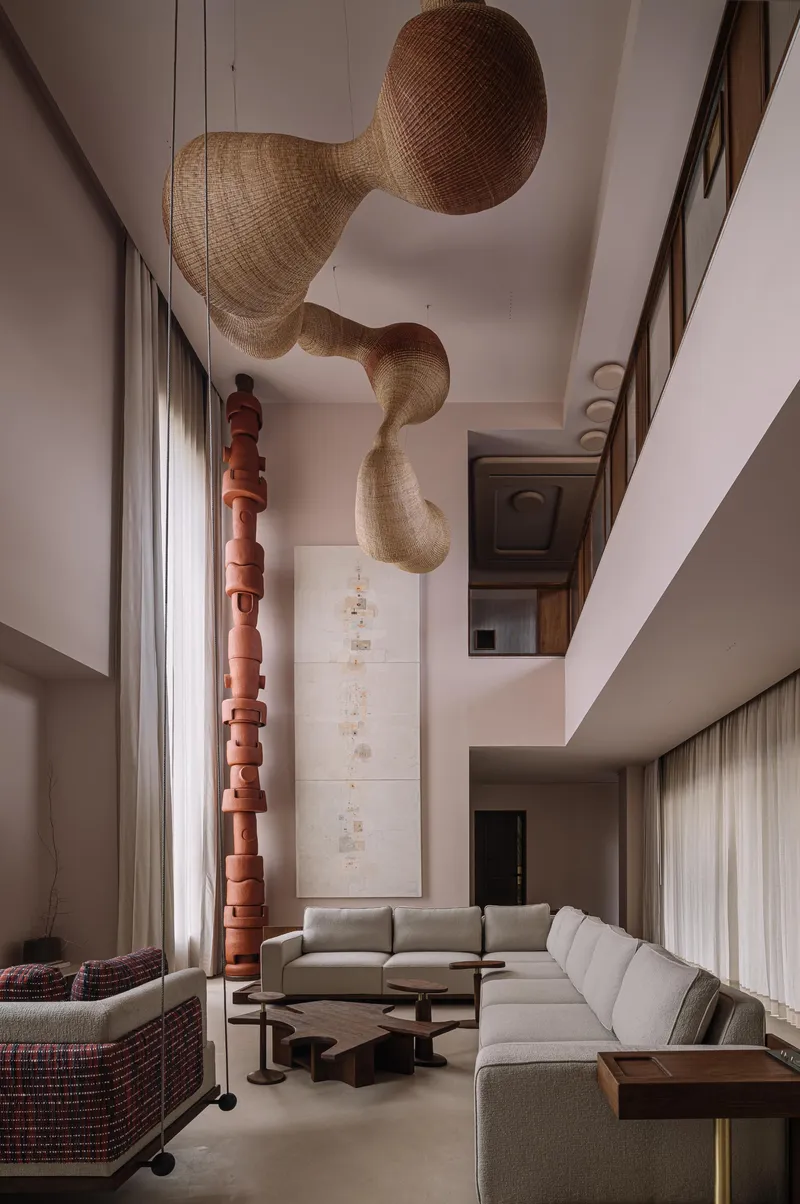Double-height living space with woven pendant lights and a sculptural terracotta column beside sectional seating