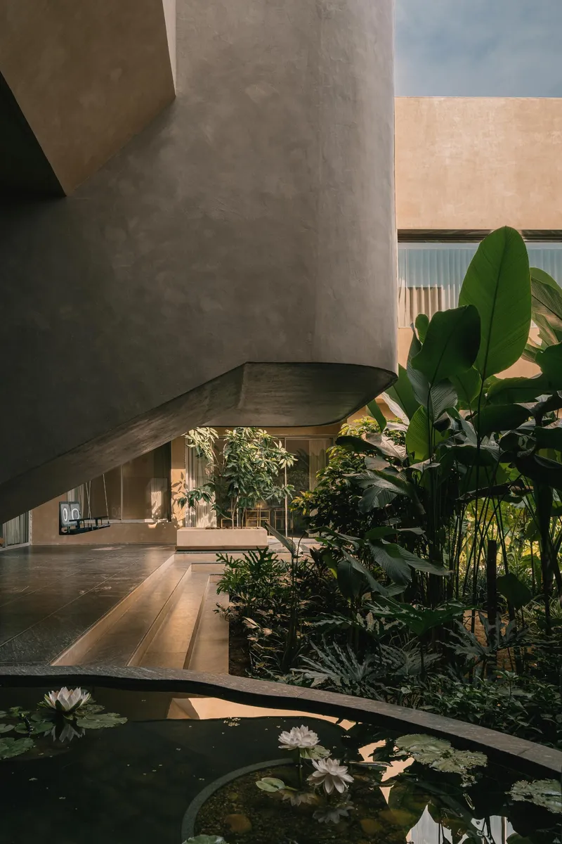 Concrete cylindrical column beside a reflecting pool with water lilies and tropical planting