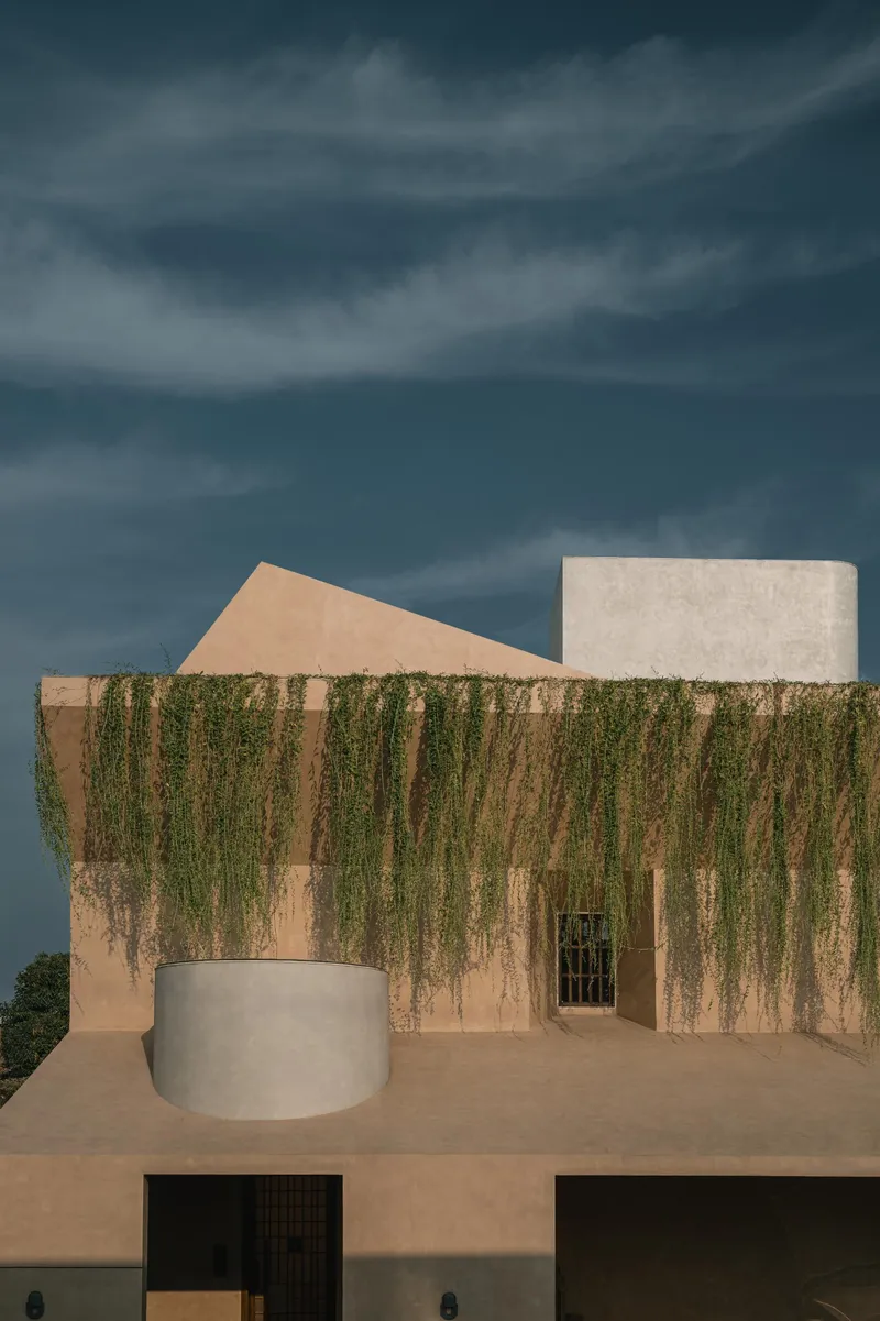 Rooftop terrace with cascading greenery over stucco walls beneath a stormy sky